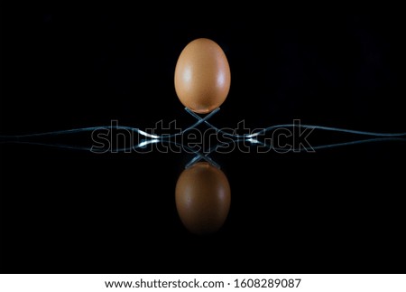 egg on two forks on black background