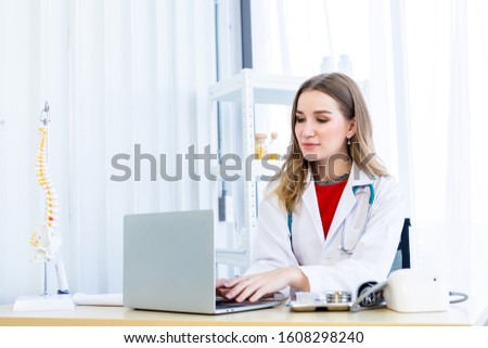 female doctor with stethoscope working with laptop computer on wooden table in Hospital background