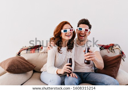 Funny young people watching movie in 3d glasses. Couple spending valentine's day at home.