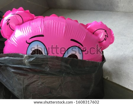 Pink balloon bear half in black rubbishy bin. Funny expression with space for runaround or wraparound text concept of koala being scared and sad