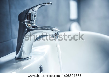 Faucet and water drop close up. Bathroom interior with sink and water tap.