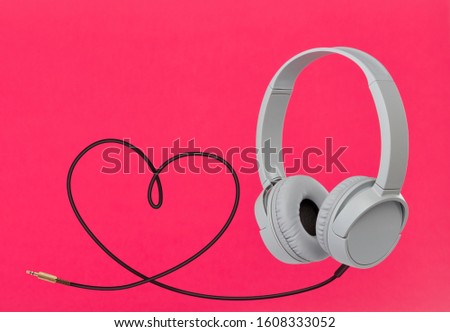 Headphones with hearth shaped cable on pink wallpaper