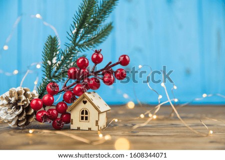 Happy new year and Merry Christmas cozy concept. Beautiful Christmas tree branch, new year decoration, lights, balls and toy house on wooden background