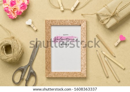 Mockup photo frame with kraft present boxes and craft rose flower for Valentines day concept. Top view of mock up photo frame with craft decoration and on wood background. Top view with copy space.