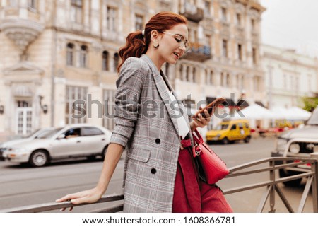 Red haired woman in stylish outfit chatting on phone Royalty-Free Stock Photo #1608366781