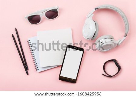 Top view mock up with phone, Fitness tracker, headphones, glasses, notebook on pink background. Copy space. 'To do' list. Planning of walk route, to-do list or shopping. Smart Band Sport bracelet app