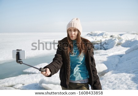 Female traveler at Jokulsarlon Glacial Lagoon using monopod to make selfie picture