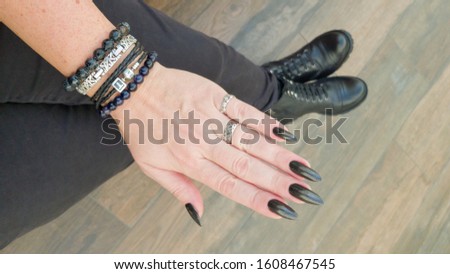 Female hand with long nails and black manicure with bottles of nail polish