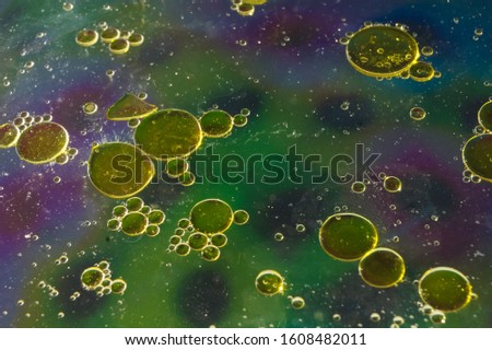 Abstract background colored oil stains on water. Water bubbles. Macro shot of air in water. Cosmic with green background. 