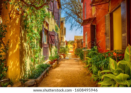 Street on Gorée island, Senegal, Africa. They are colorful stone houses overgrown with many green flowers. It is one of the earliest European settlements in Western Africa, Dakar Royalty-Free Stock Photo #1608495946