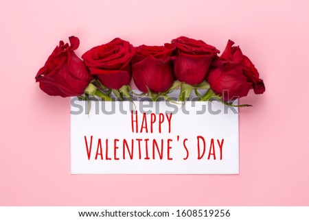 Happy valentine's day banner. Red rose flowers arrangement with blank card on light pink background. Copy space. Top view