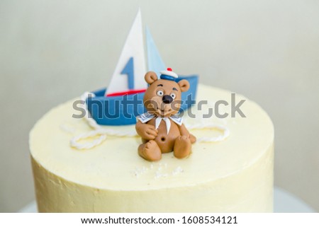 1 year old boy birthday cake with boat and sailor teddy bear for thematic sea party.