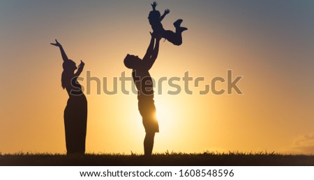 Mother father playing with son throwing him up in the air. Happy family outdoors in the park. 
