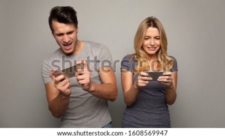 Excited gamers. Close up photo of a young couple, who are playing games together on their smartphones, experiencing tension during the game.