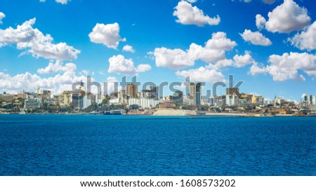 View of the Senegal capital of Dakar, Africa. It is a city panorama taken from a boat. There are large modern buildings and a blue sky with clouds. Royalty-Free Stock Photo #1608573202