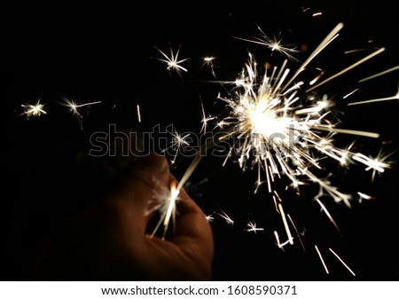 A man lights bright sparklers on New Year's Eve. Winter holidays with family in nature.