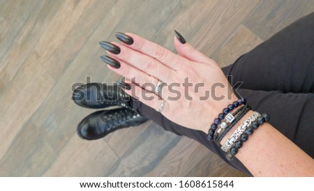 Female hand with long nails and black manicure with bottles of nail polish