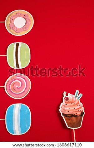Muffin and doughnuts and paper bun on a wooden stick on a red background for birthday, Valentine's Day, wedding and other holidays, view from the top.