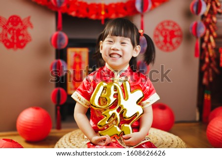 Chinese toddler girl traditional dressing up hold a Fu means 'lucky' greeting sign