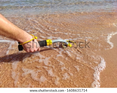 The photo of an underwater metal detector vel on the sand.Treasure searching and tourist adventure background.