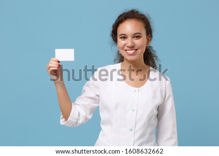 Smiling african american doctor woman isolated on blue background. Female doctor in white medical gown holding blank empty credit bank card. Healthcare personnel medicine concept. Mock up copy space