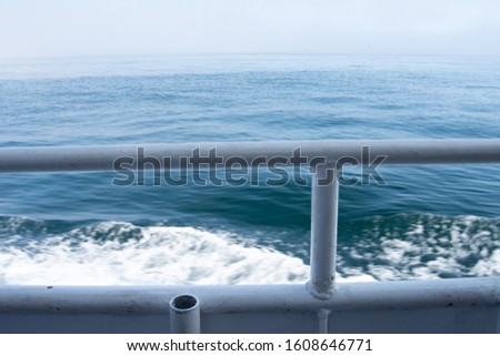 view from behind the hand railing of waves and ripples waves being created by a ferry boat 