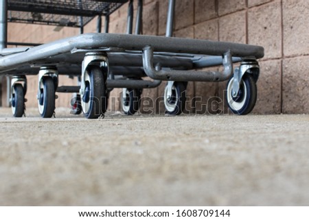 close up of metal gray shopping cart wheels on gray cement walkway next to cinder block exterior