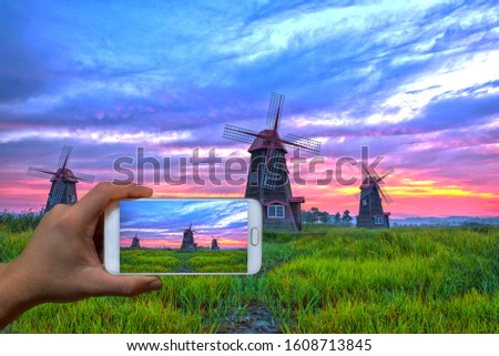 Hand taking picture of windmills with cell phone  at Sorae ecological park in South Korea