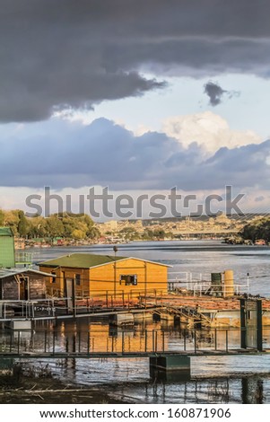 Panoramic photograph of Belgrade cloudy dusk skyline, with raft houses on Sava river banks and the City downtown, with the Bridge Over Ada pylon in the background.