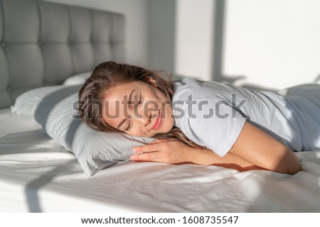 Bed Asian girl happy smiling sleeping on stomach sleeper resting head on foam pillow. Healthy sleep. Royalty-Free Stock Photo #1608735547