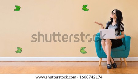 Green leaves with young woman using a laptop computer