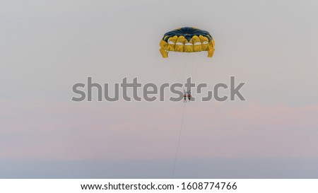A paraglider couple on the background of a romantic expressive and empty sky is enjoying the last rays of sunlight