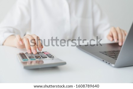 Business woman hand press calculator and calculate monthly expenses on table in office home.