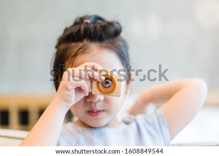 Little asian girl holding Wooden toy camera and take picture.Concept for photography, Photo Education.Kid talent and eye care.
