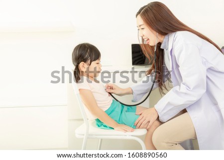 The female doctor is examining the girls. Female doctor examining little girl with stethoscope. young woman doctor examining a child patient in white room.