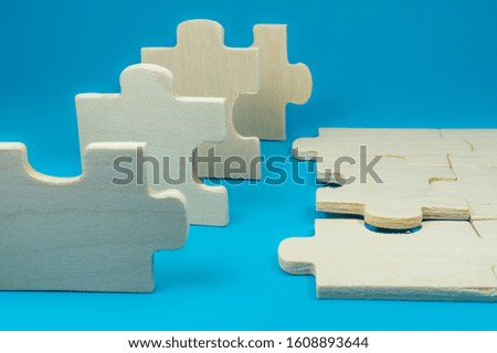 Pieces of wooden puzzle game made of white unpainted plywood viewed in close-up on blue surface background