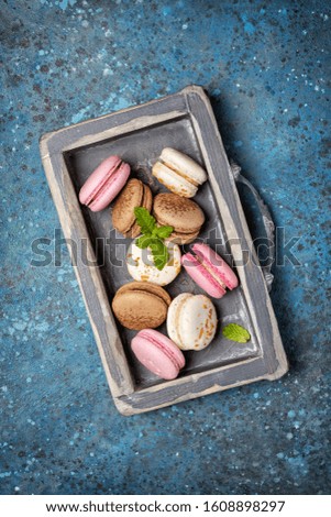 Top view of french dessert tasty macaroons with fresh mint on blue concrete background