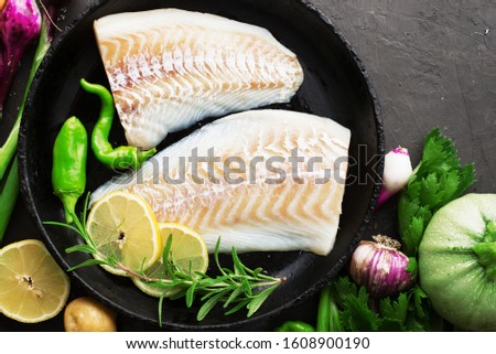 Fresh raw fillet of sea white cod fish with organic fresh juicy vegetables and herbs before cooking. Concept again of any healthy diet, protein and vegetables. Top view.