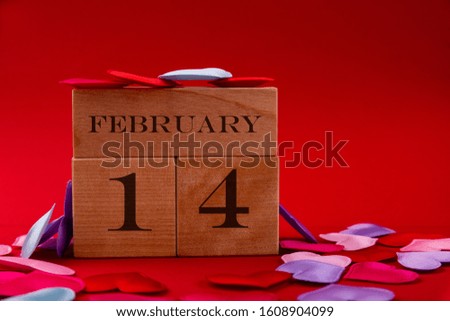 Wooden cubes with the inscription February 14 and small hearts on a red background