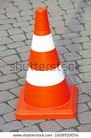 traffic cone with white and orange stripes on the road