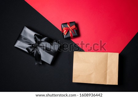 Top view of gift box with red, shopping paper bag, black ribbons and piggy bank isolated on red and black background. Shopping concept boxing day and black Friday sale composition.
