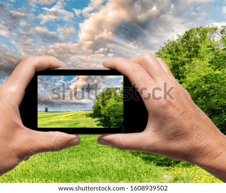 Man and woman hand capturing Tuscany spring landscape with smartphone.