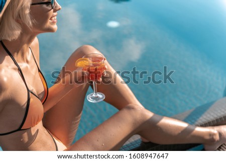 Beautiful lady in swimsuit enjoying drink and relaxing by the pool stock photo. Website banner