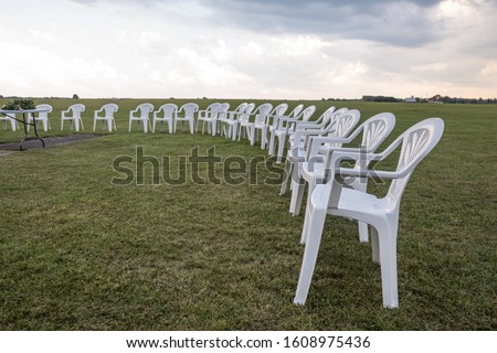 White plastic chairs on a meadow arranged in a circle for meditation.