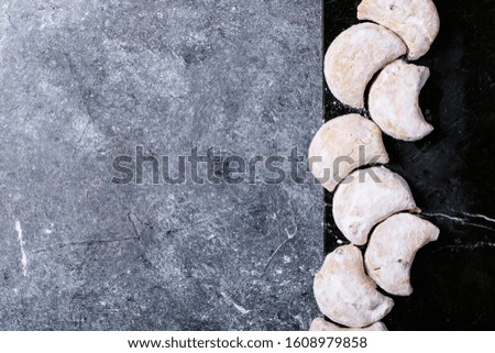 Variety of traditional Greek sweets cookies kourabiedes and akanes lukum in sugar powder over blue texture background. Top view, flat lay