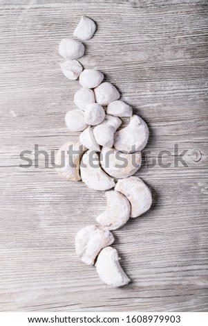 Variety of traditional Greek sweets cookies kourabiedes and akanes lukum in sugar powder over gray wooden texture background. Top view, flat lay