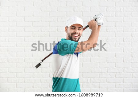 Handsome male golfer on white brick background