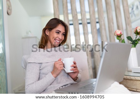 Excited woman reading good news on laptop screen at home and drinking coffee. Happy female chatting, shopping online, writing email, scrolling network, watching video on computer.