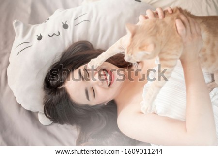 Beautiful asian  cat lover woman is playing with cat in her room 