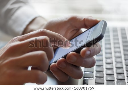 Leader contacting his business team with smartphone and laptop at hand Royalty-Free Stock Photo #160901759